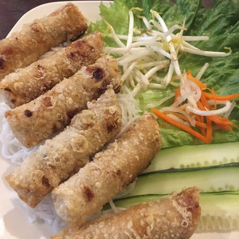 Crispy Vietnamese spring rolls with vermicelli noodles, lettuce, bean sprouts, pickled carrots, and cucumber slices.